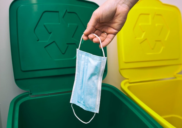 The woman throwing the medical mask into one of three trash bins