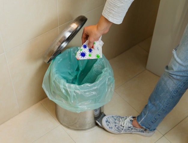 Woman throwing napkin with virus in trash can. COVID-19 concept. Coronavirus.
