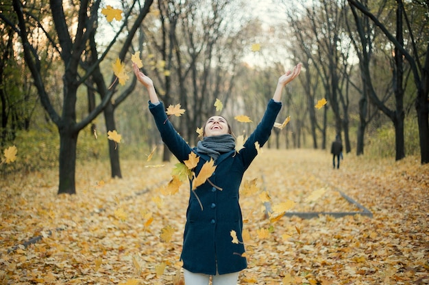 Woman throwing yellow leaves in the air