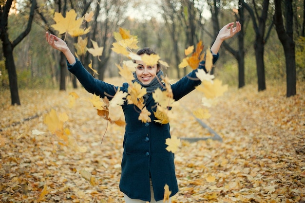 Woman throwing yellow leaves in the air