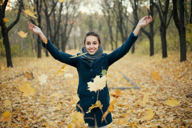 Woman throwing yellow leaves in the air