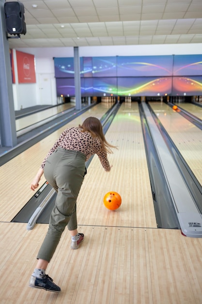 A woman throws a ball into a bowling alley. Paths with balls and pins for bowling.