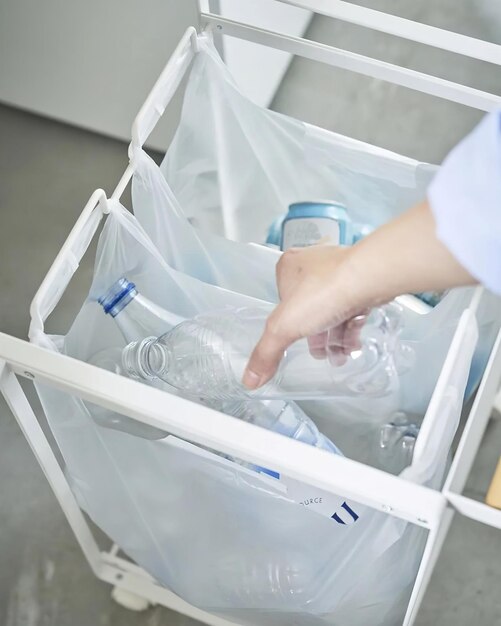 Женщина выбрасывает пластиковую бутылку в отдельный мусорный контейнер
