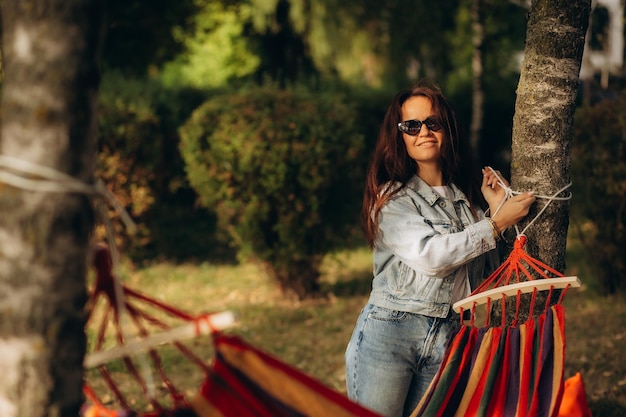 A woman ties a hammock to a tree