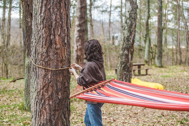 Woman ties up hammock in forest between trees