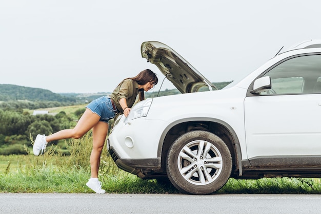 Woman in tight shirts new broken car with opened hood