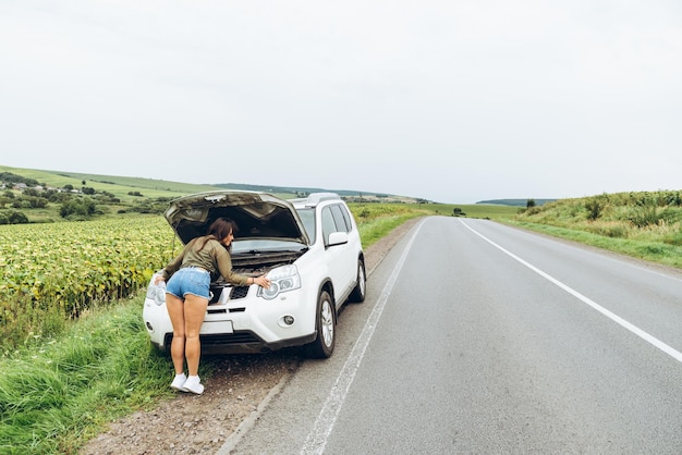 Woman in tight shirts new broken car with opened hood