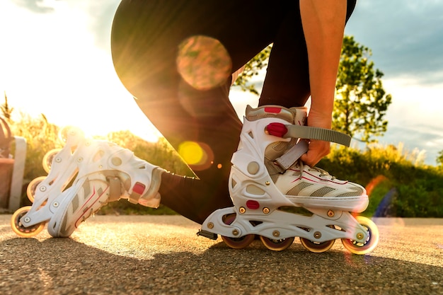 Una donna stringe i pattini sul percorso. le gambe della donna con le lame al giorno soleggiato.