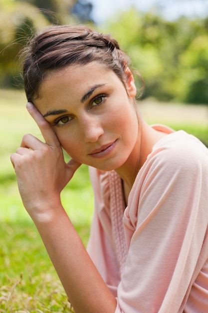 Woman tilting her head against her fingers while lying on her front