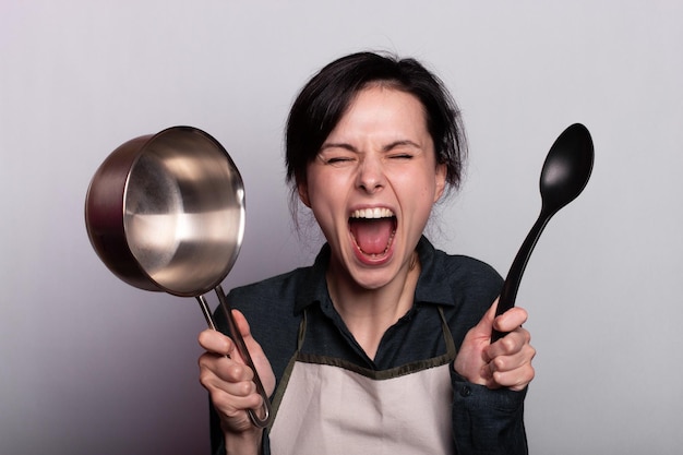 woman tired of cooking holding dishes in her hands