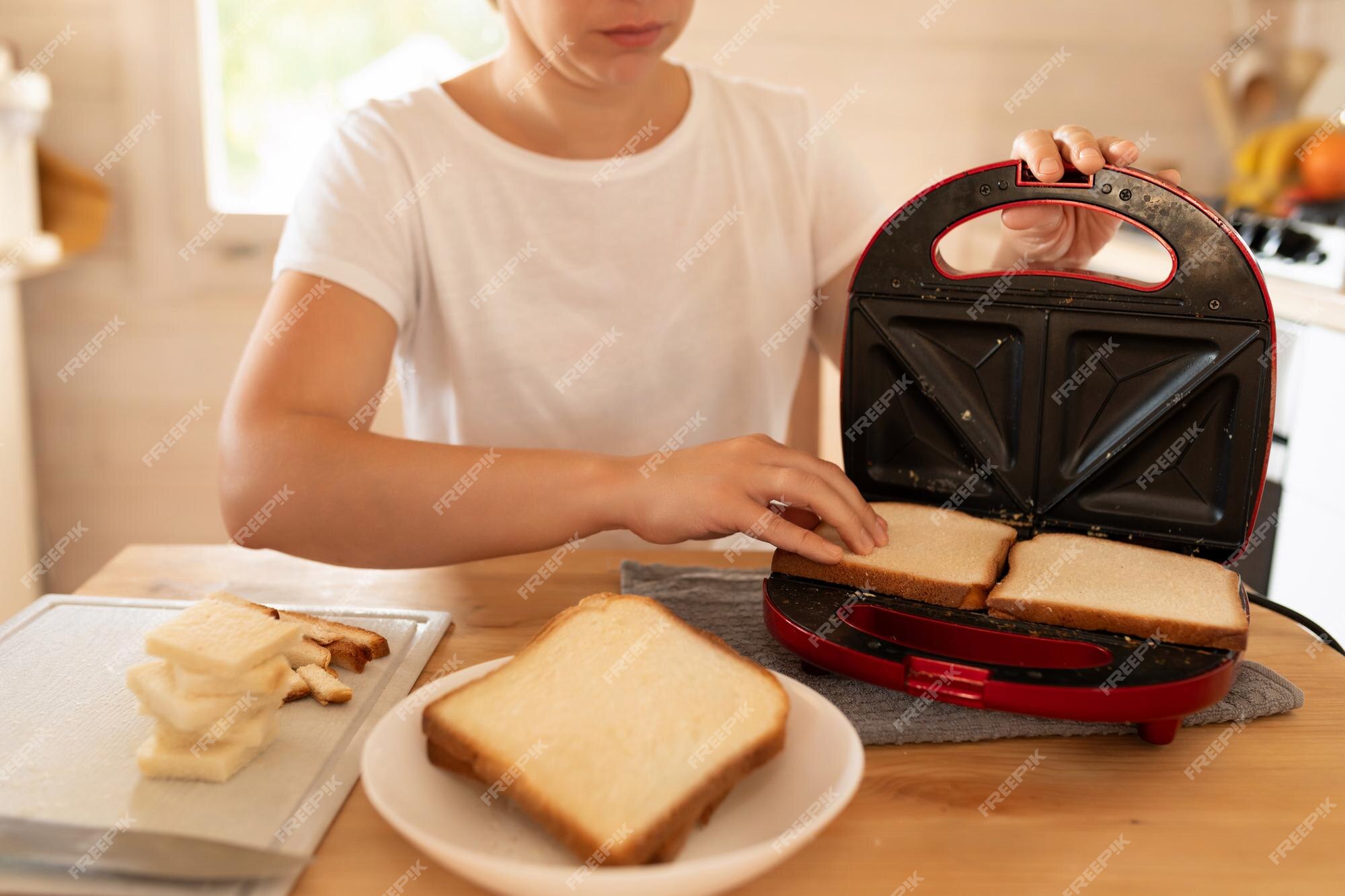 Premium Photo  Employed cook putting a sandwich on a toaster grill for  toasting in a restaurant