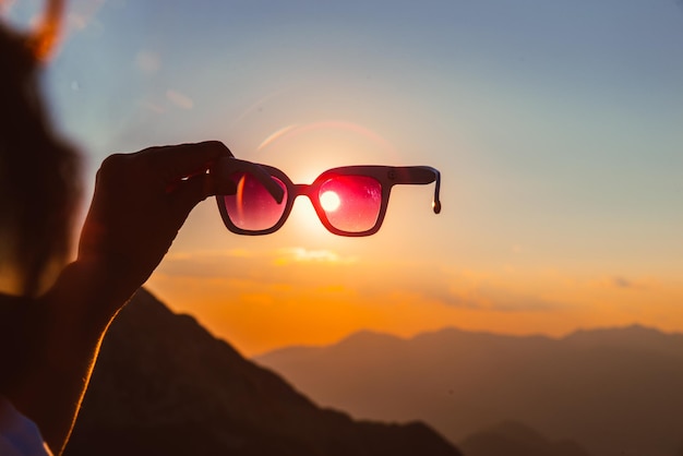 Woman on the top of the mount on sunset sunlight through sunglasses. travel lifestyle