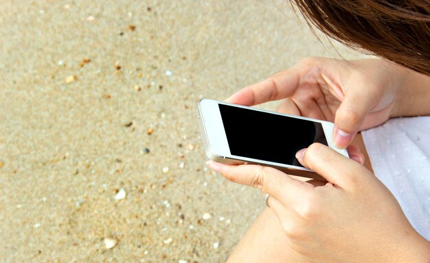 woman touch screen cell phone on sand