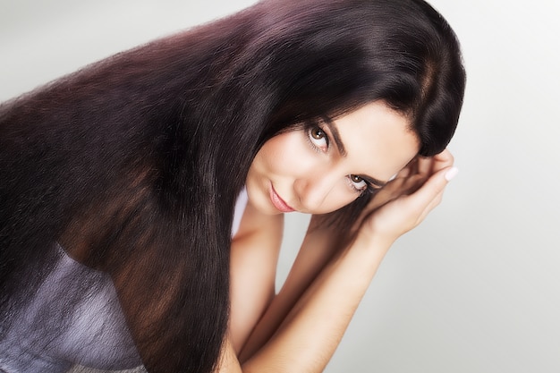 Woman touches her long and healthy brown hair.
