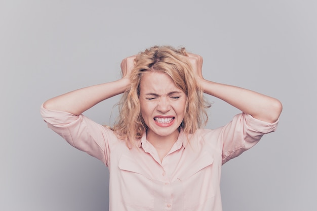 Woman touching hair crazy in madness isolated over grey