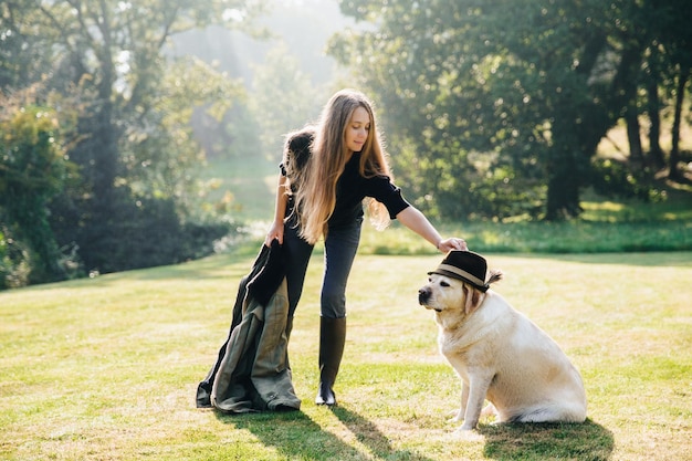 犬の頭の上の帽子に触れる女性