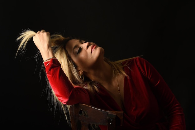 Woman touching her hair on black background