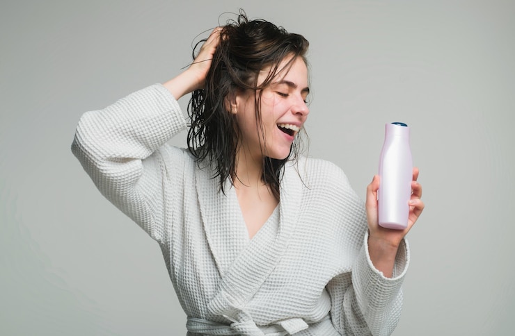 Photo woman touching her hair woman hold bottle shampoo and conditioner happy young woman with balm bottle