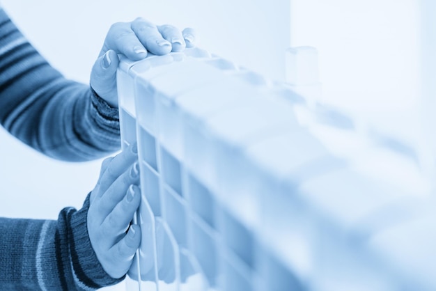 Woman touching warm radiator with both hands