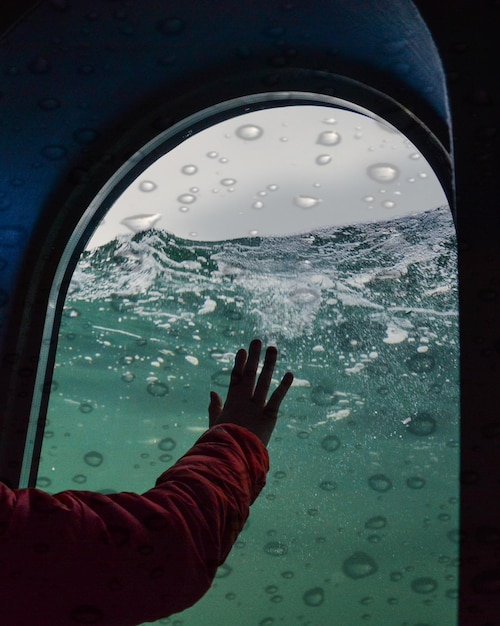 Foto donna che tocca la finestra sott'acqua