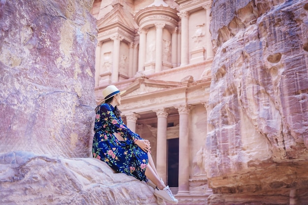 woman tourist in color dress and hat enjoying the Treasury, Al Khazneh in the ancient city of Petra, Jordan