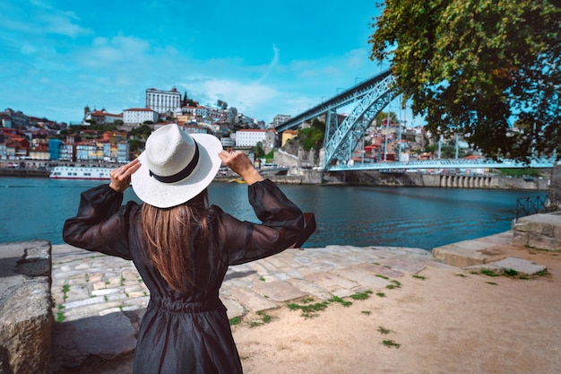 Woman tourist enjoying beautiful view of Porto city old town with river and famous iron bridge