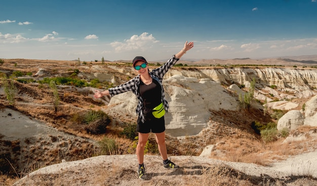 Woman tourist on hill top with open arms during mountain hike in Cappadocia, Turkey