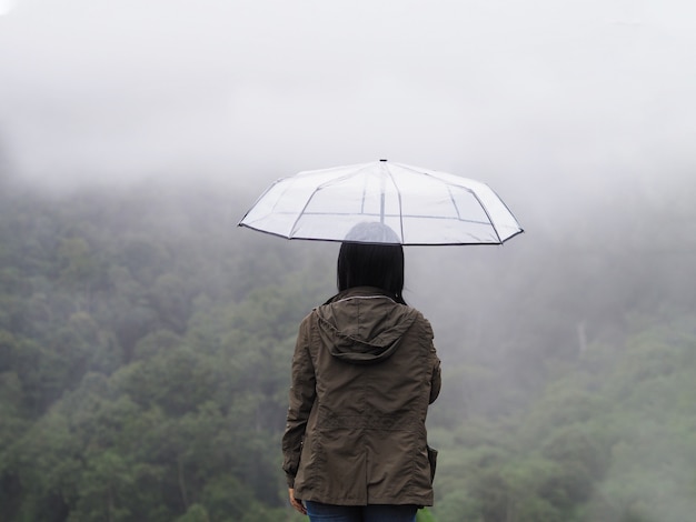 woman tourist hold umbrella over green rain forest background.