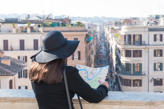 Woman tourist is looking at the map on the street of city