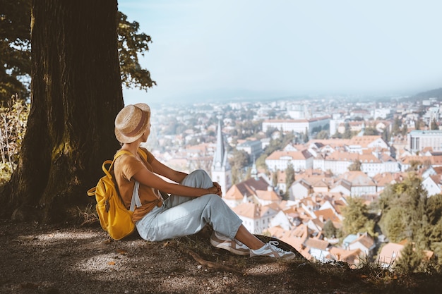 Woman tourist looking at panoramic view cityscape with red roofs of Ljubljana from City Castle