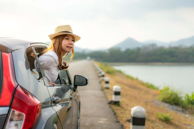 遠征旅行休暇で運転するとき、窓の外の景色を探している女性観光客。