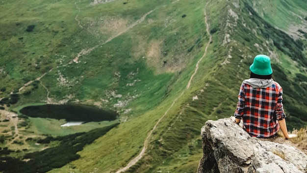 Woman tourist sitting on the background of green mountains and a lake