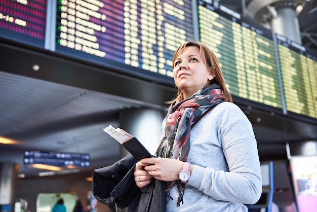 Woman tourist standing at the airport on the background of departures and arrivals