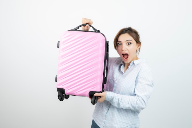 Женщина-туристка стоит и держит розовый чемодан. фото высокого качества