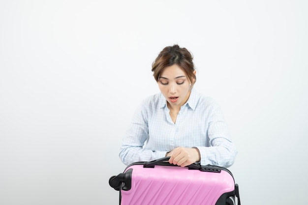 Woman tourist standing and holding pink travel suitcase . High quality photo