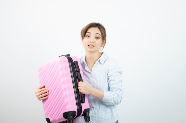 Woman tourist standing and holding pink travel suitcase . High quality photo