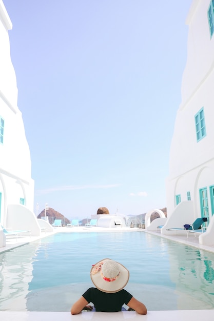 Woman tourist in summer hat relaxing on the pool on summer day