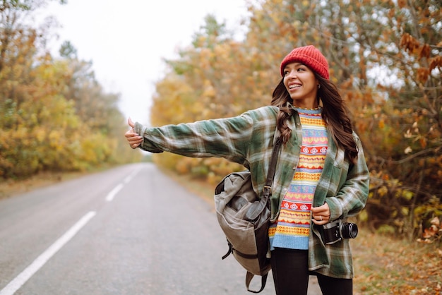 Woman tourist taking pictures in autumn forest Relaxation tourism nature lifestyle concept