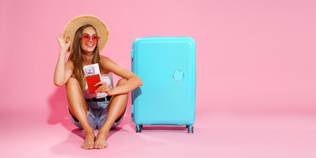 Женщина-турист-путешественница с чемоданом для паспорта и билетов с белыми шортами и соломенной шляпой