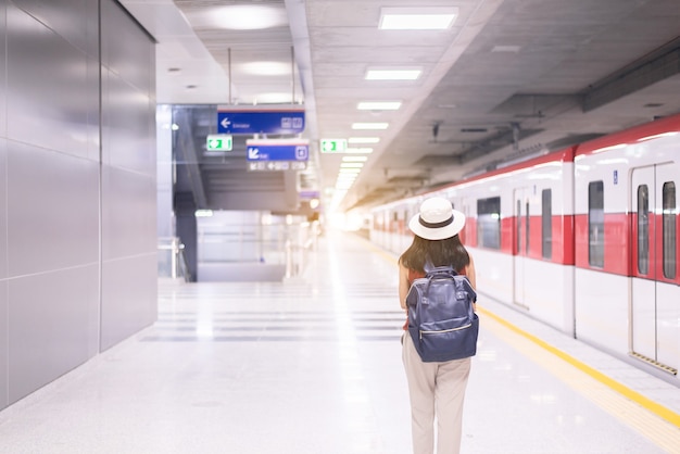 駅で電車を待っている女性観光客、旅行と休暇の概念、背面図