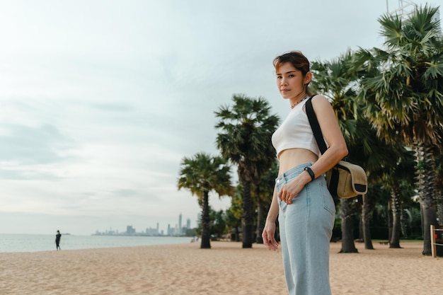 Woman tourist walk on the beach with palm trees on the background