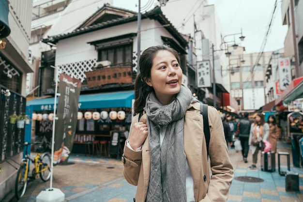 Женщина-туристка гуляет по цутенкаку во время путешествия по японии. счастливая азиатская девушка-туристка на продовольственной улице во время летних каникул. улыбающаяся путешественница в поисках традиционных японских закусок на открытом рынке