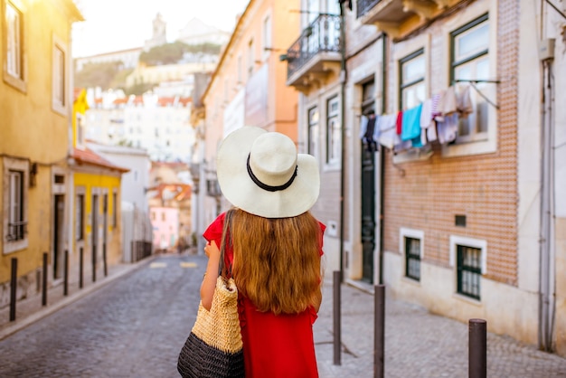 Woman tourist walking back on the narrow street in Alfama region during the morning light in Lisbon, Portugal