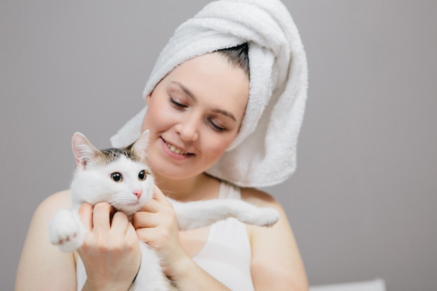 woman in a towel on her head with a cat on a light