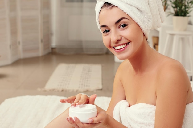 Woman in towel holding jar of cream