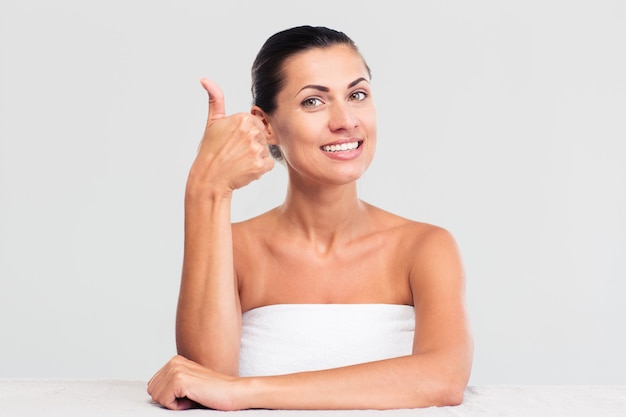 Женщина в полотенце показывает палец вверх