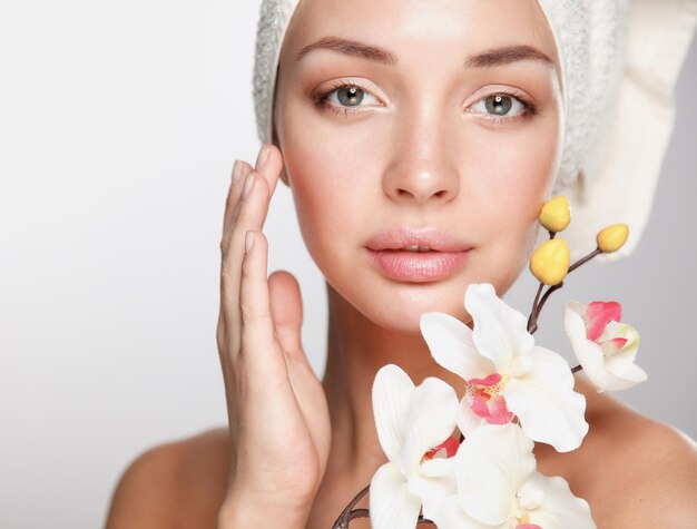 Photo woman in towel with orchid flowers .