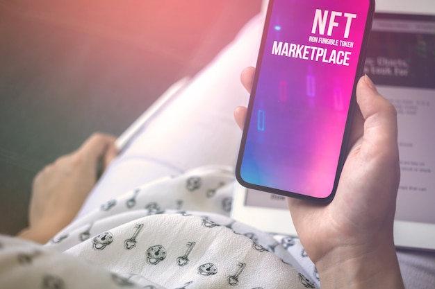 Woman trade with non fungible token on mobile phone. Logo on the screen. NFT crypto art and future of freelance concept background photo