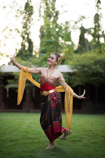 Woman in traditional clothing posing against trees