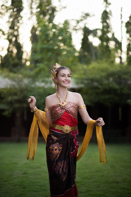 Woman in traditional clothing standing against trees